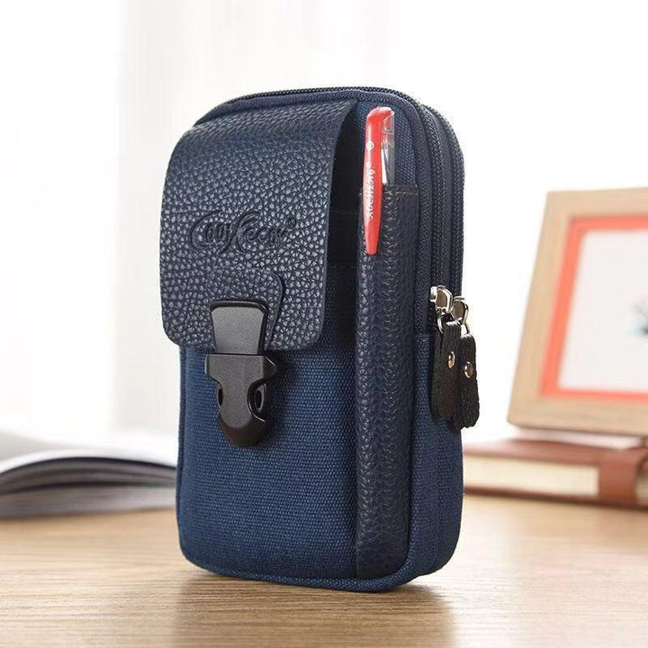 Compact navy blue canvas pouch with textured flap, front buckle closure, and pen holder on wooden desk
