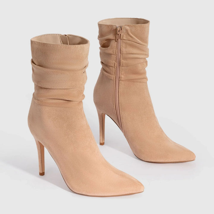 Pair of beige suede pointed-toe high heel ankle boots with side zipper and ruched shaft