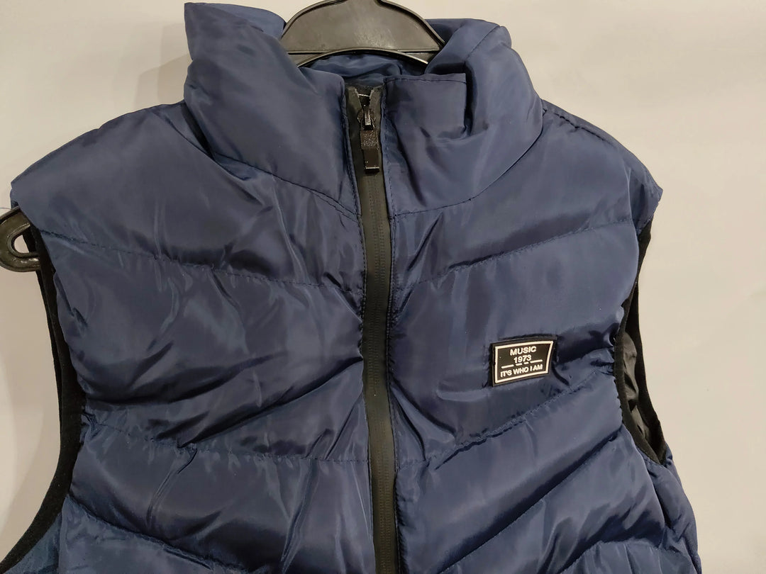 Navy blue puffer vest with front zipper and patch reading 'Music 1973 It's who I am' on hanger