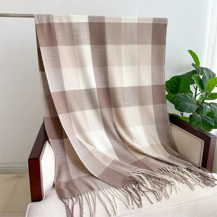Beige and brown checkered wool throw blanket draped over beige armchair with indoor plant