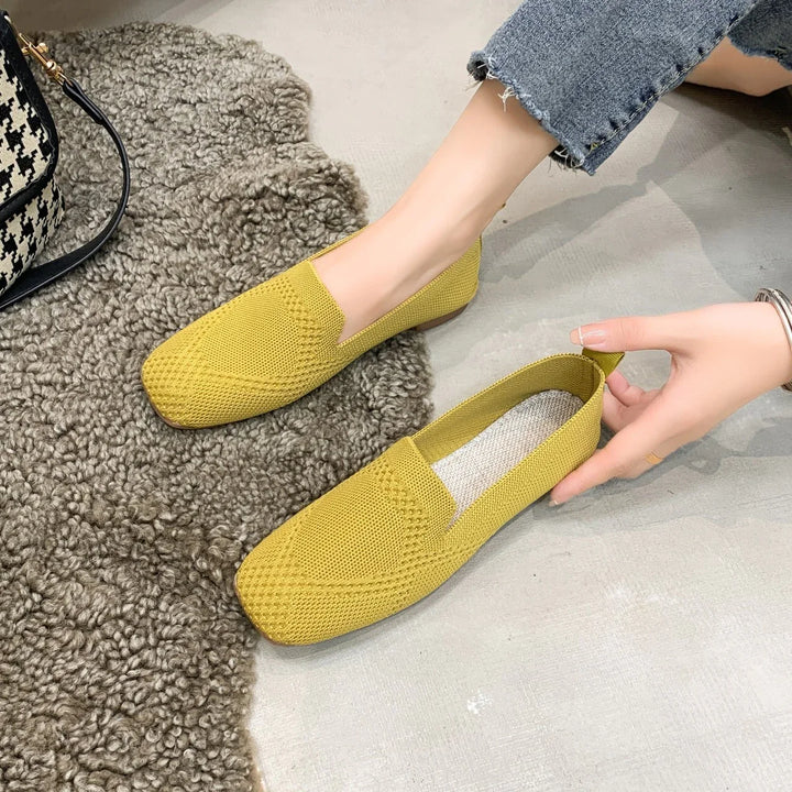 Yellow knitted casual women's loafers worn with blue cropped jeans on grey floor and brown textured rug