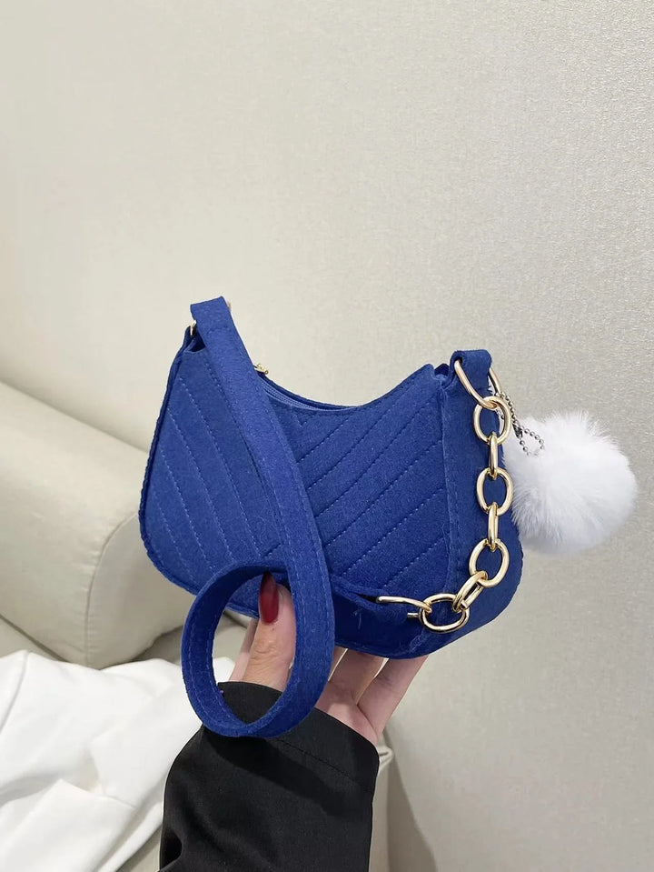 Blue quilted small handbag with gold chain and white fluffy pompom accessory