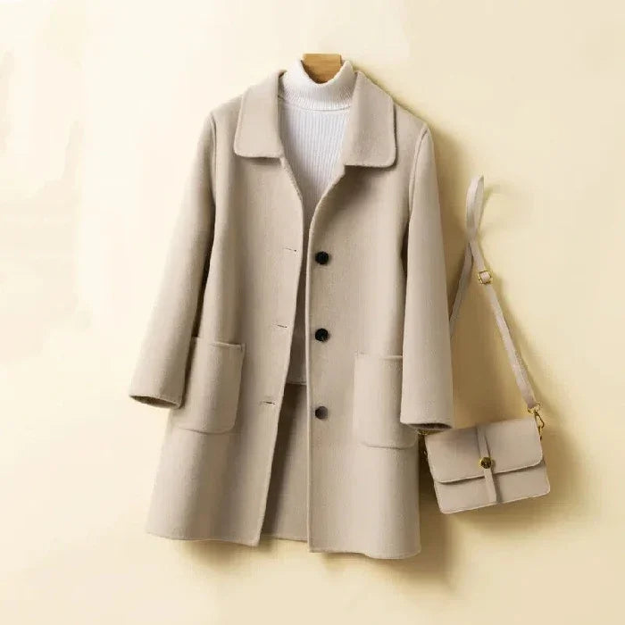 Beige wool coat with black buttons over white turtleneck sweater, paired with matching beige crossbody bag
