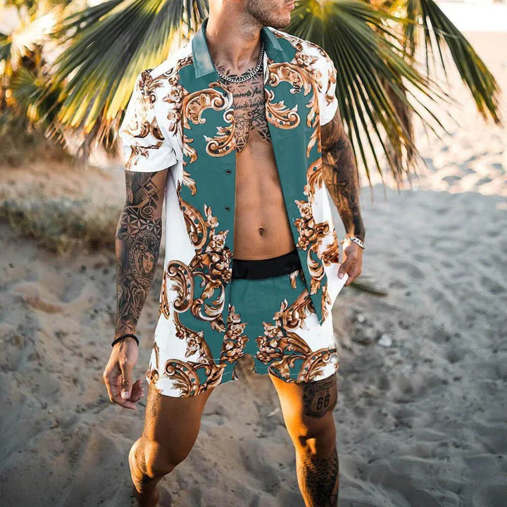 Man with tattoos wearing patterned teal and white short-sleeve shirt and matching shorts on sandy beach