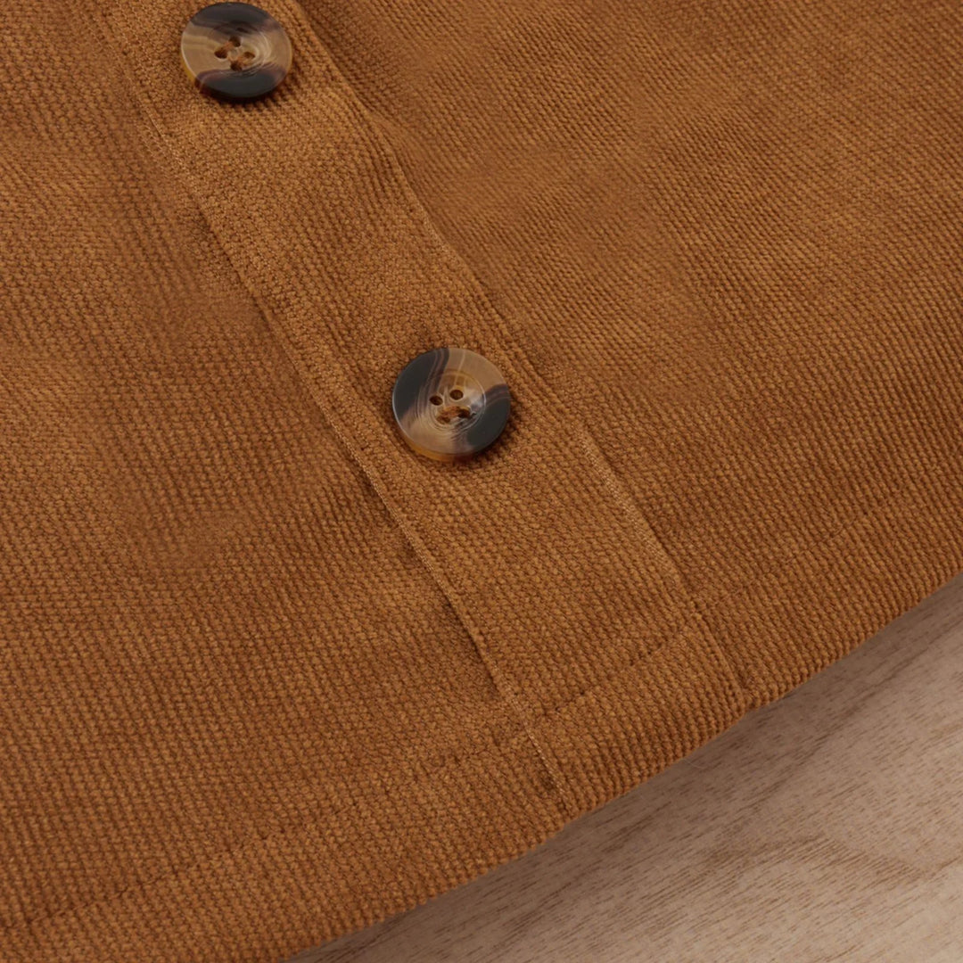 Close-up of brown corduroy fabric with two brown marbled buttons on wooden surface