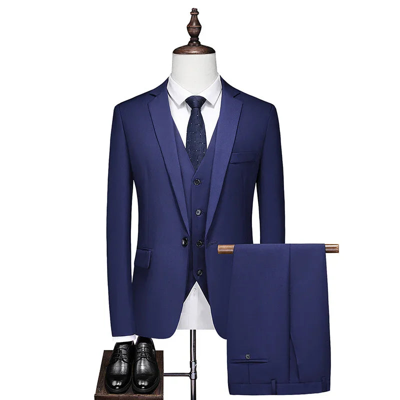 Men's blue three-piece suit with white shirt, navy tie, matching trousers, and black formal shoes