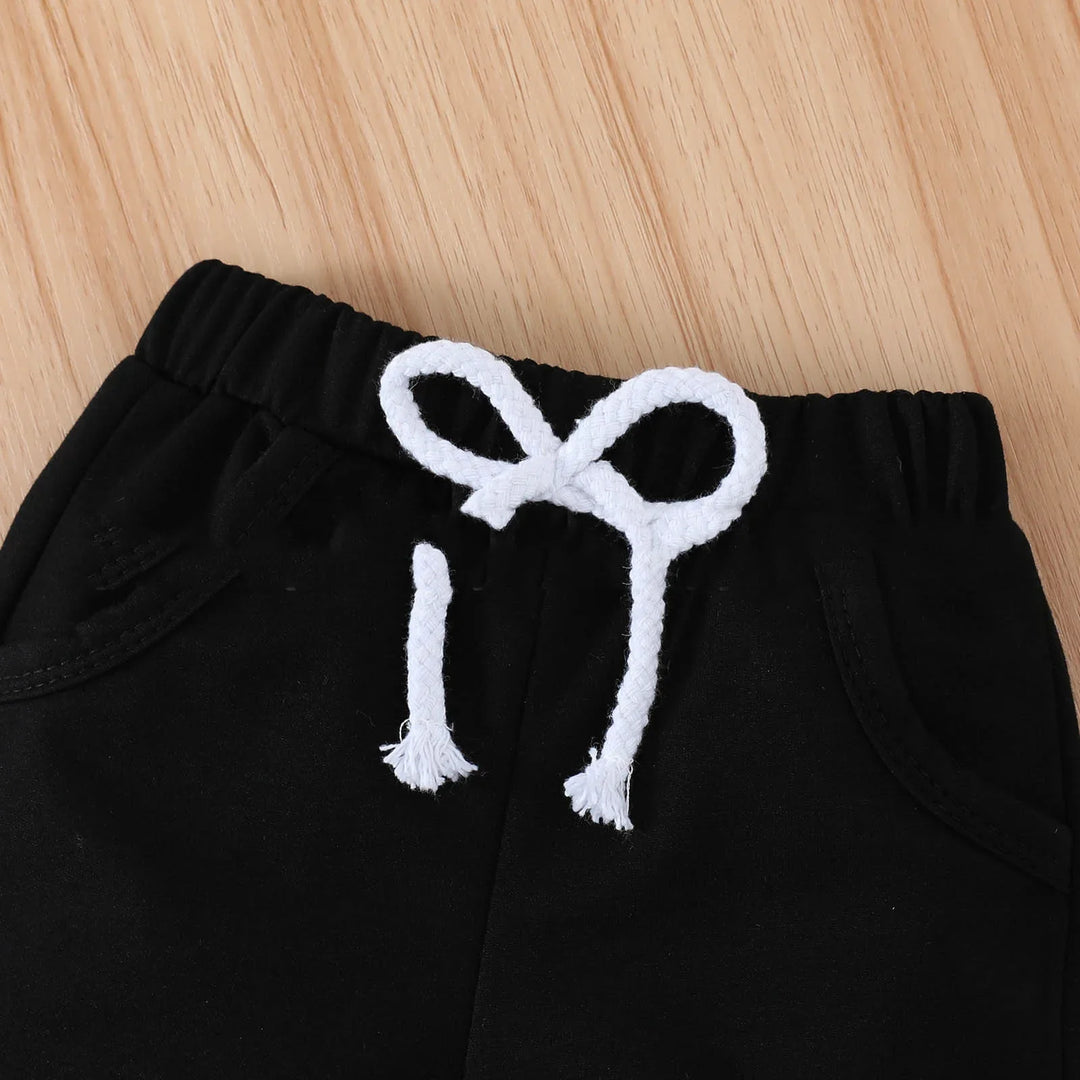 Close-up of black sweatpants with white drawstring bow on wooden surface