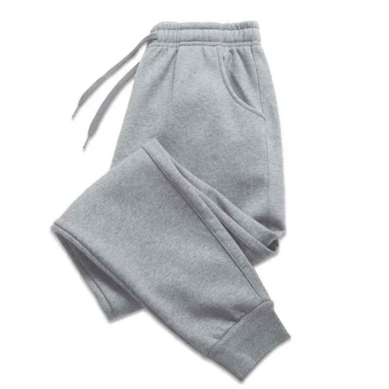 Folded light gray sweatpants with elastic waistband, drawstrings, side pockets, and cuffed ankles