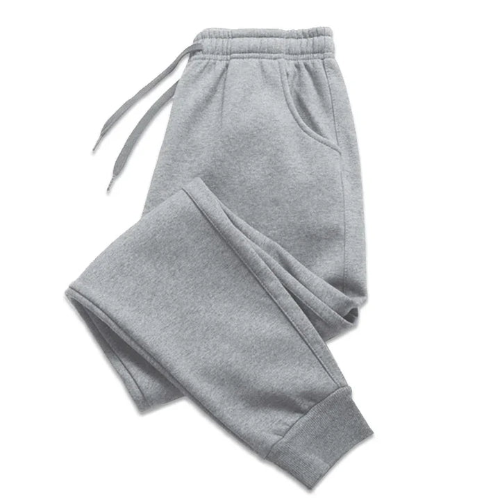 Folded light gray sweatpants with elastic waistband, drawstrings, side pockets, and cuffed ankles