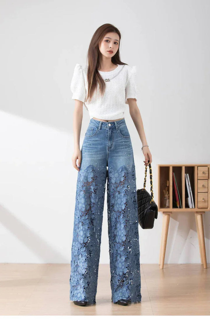 Woman wearing white puff-sleeve top and blue wide-leg jeans with floral lace cutouts, holding black quilted bag