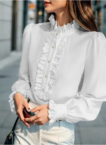 Woman wearing white ruffled blouse with pearl buttons and puff sleeves holding a black purse