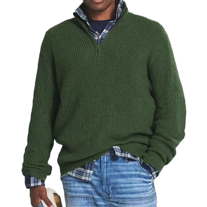 Man wearing textured dark green quarter-zip sweater over blue plaid shirt with light wash denim jeans