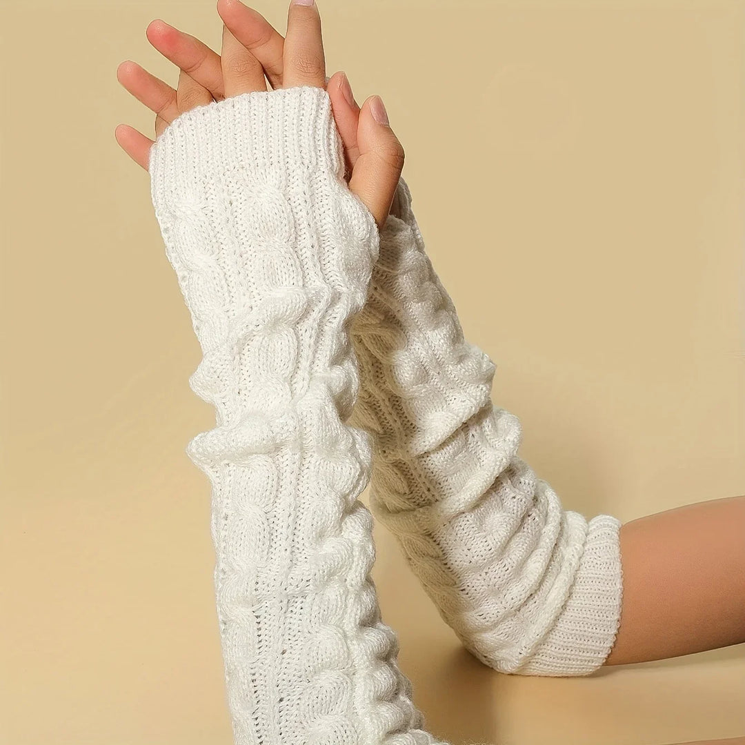 Close-up of hands wearing white cable knit arm warmers on beige background
