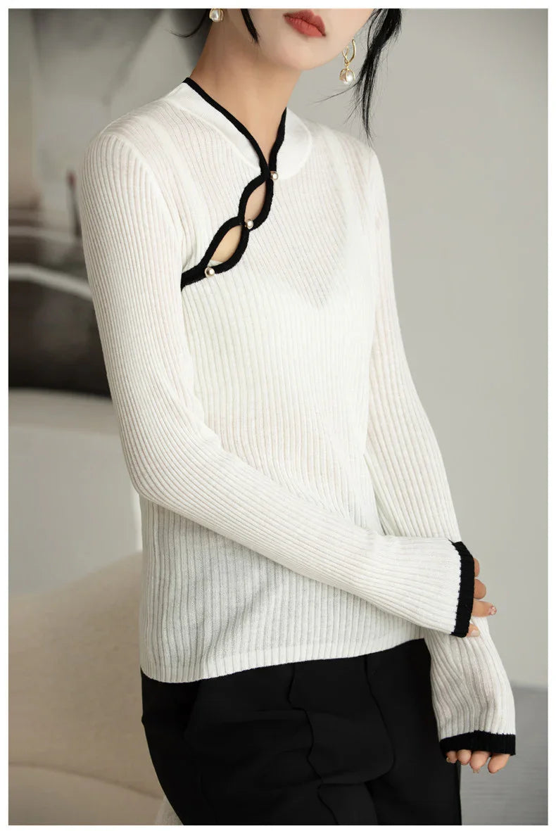 Woman wearing white ribbed sweater with black trim and pearl button details