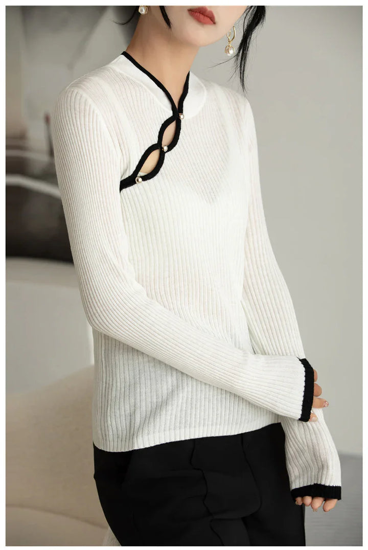 Woman wearing white ribbed sweater with black trim and pearl button details