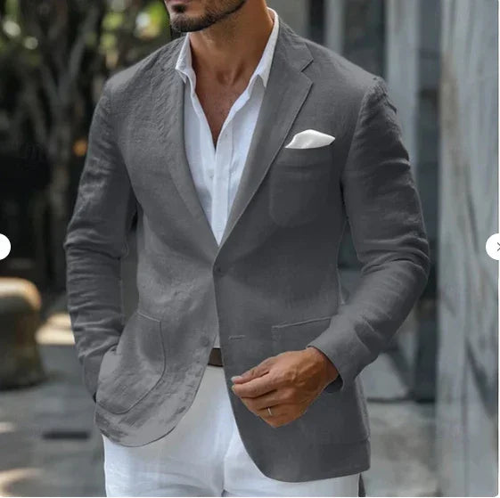 Man wearing stylish grey blazer with white pocket square and open white shirt in outdoor setting