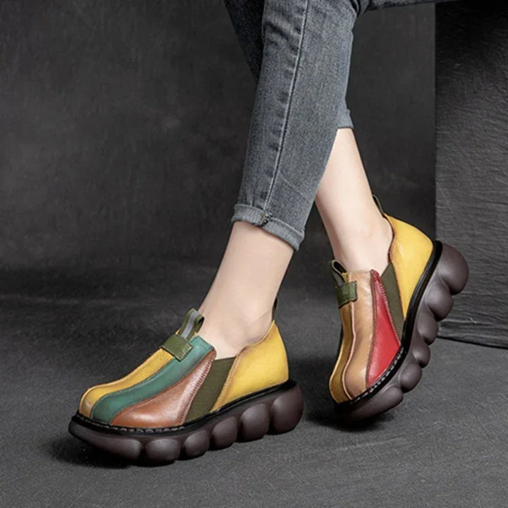 Colorful casual slip-on shoes with thick bubble soles worn with rolled-up jeans on gray background