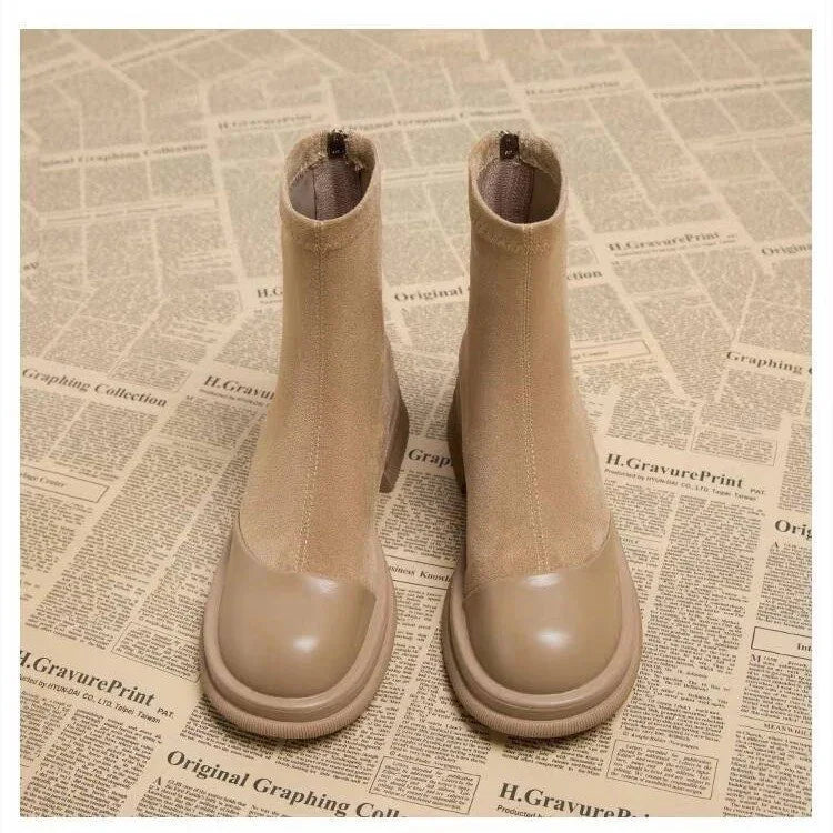 Pair of beige ankle boots with rounded toes on a vintage newspaper background