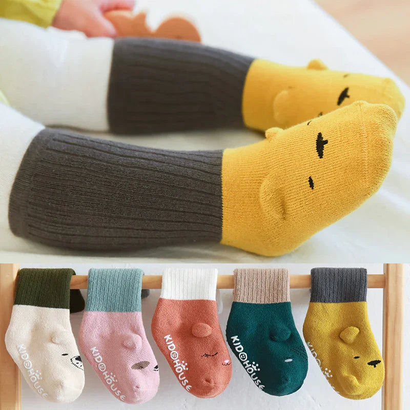Kid wearing yellow and gray ribbed cartoon animal socks with five colorful animal face socks displayed