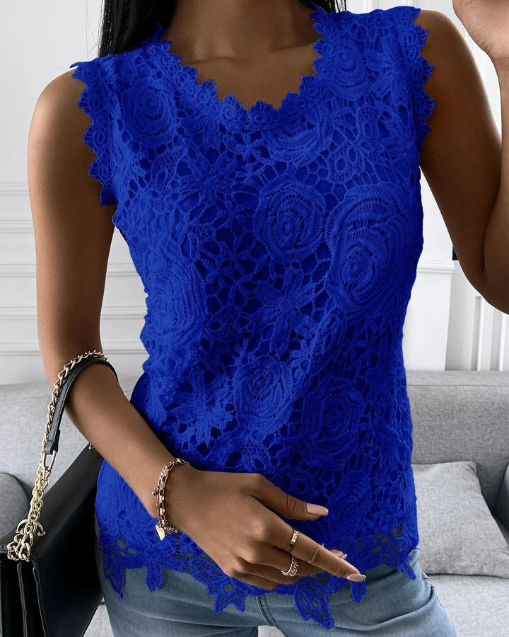 Close-up of woman wearing royal blue lace sleeveless top with floral pattern and scalloped edges