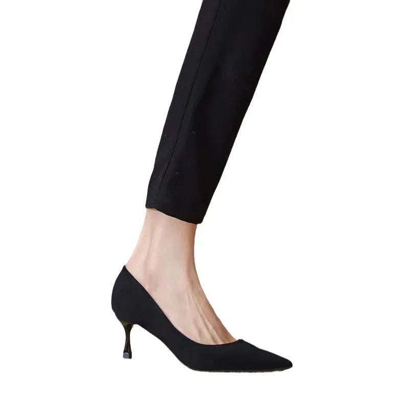 Woman wearing black pointed-toe kitten heel shoes with slim black pants on white background