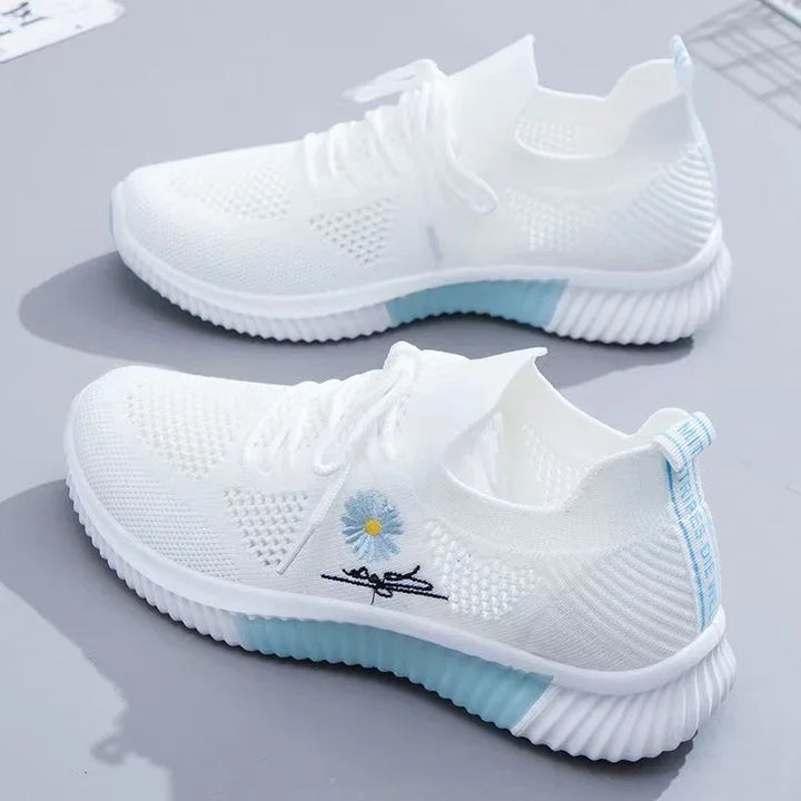 White knitted sneakers with light blue sole accents and embroidered blue flower detail on side