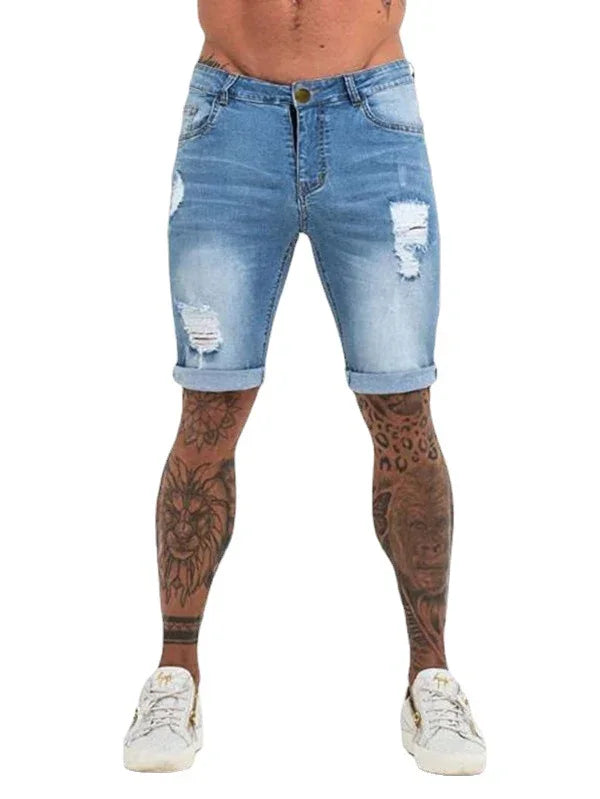Man wearing ripped blue denim shorts with rolled cuffs and white sneakers, showing tattooed legs
