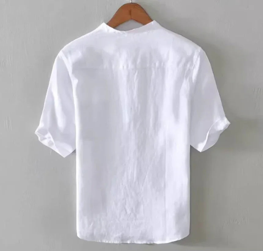 Back view of a plain white short-sleeve shirt hanging on wooden hanger against gray wall