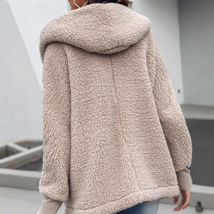 Back view of woman wearing beige sherpa fleece hooded jacket with textured soft fabric