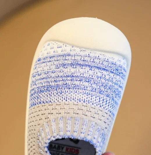Close-up of a baby kids sneaker with blue and white knit upper and white rubber sole