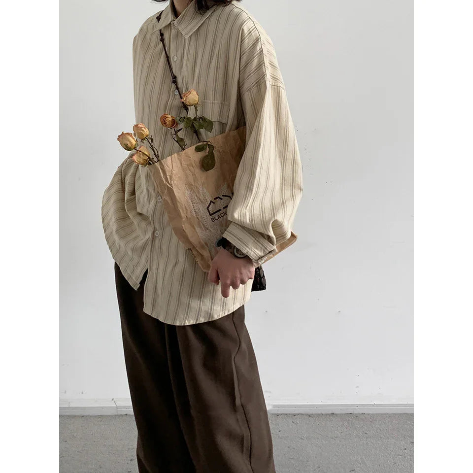 Person wearing beige striped shirt and dark pants holding brown paper bag with dried roses indoors
