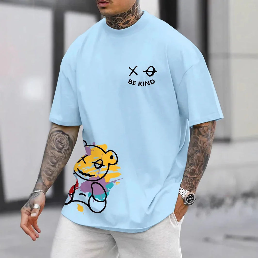 Man wearing light blue T-shirt with colorful teddy bear print and black text 'BE KIND' on chest