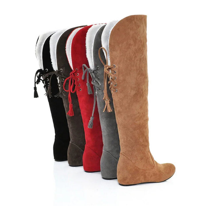 Lineup of women's knee-high winter boots in black, brown, red, gray, and tan suede with white fur trim and lace-up tassels