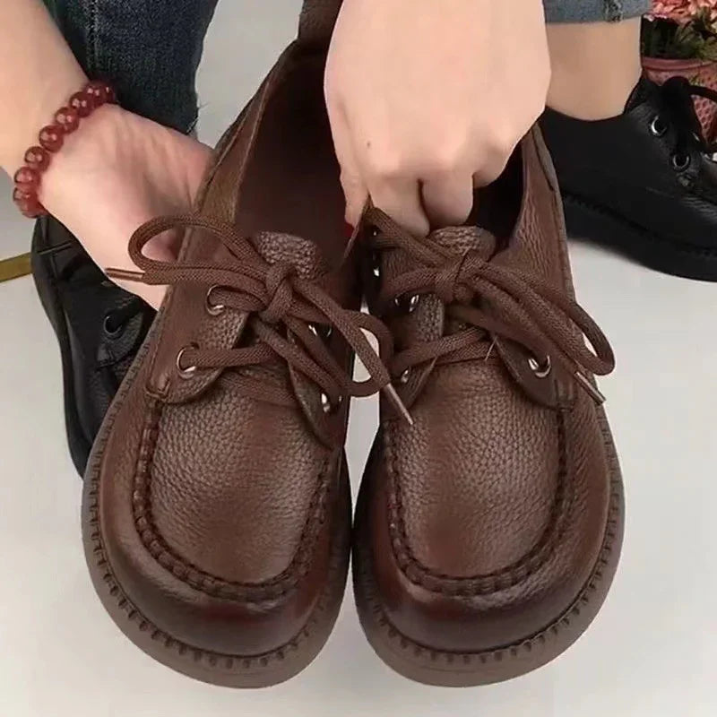 Hands holding brown leather lace-up casual shoes with thick soles on white background