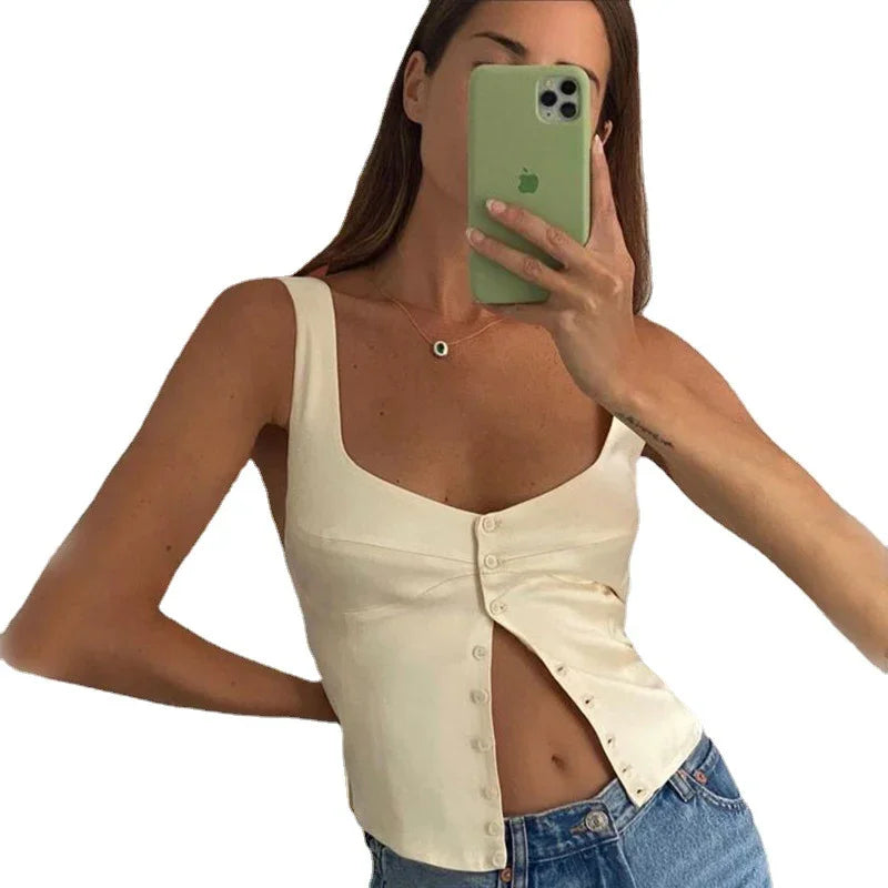 Woman wearing cream sleeveless buttoned top paired with blue denim jeans taking a mirror selfie