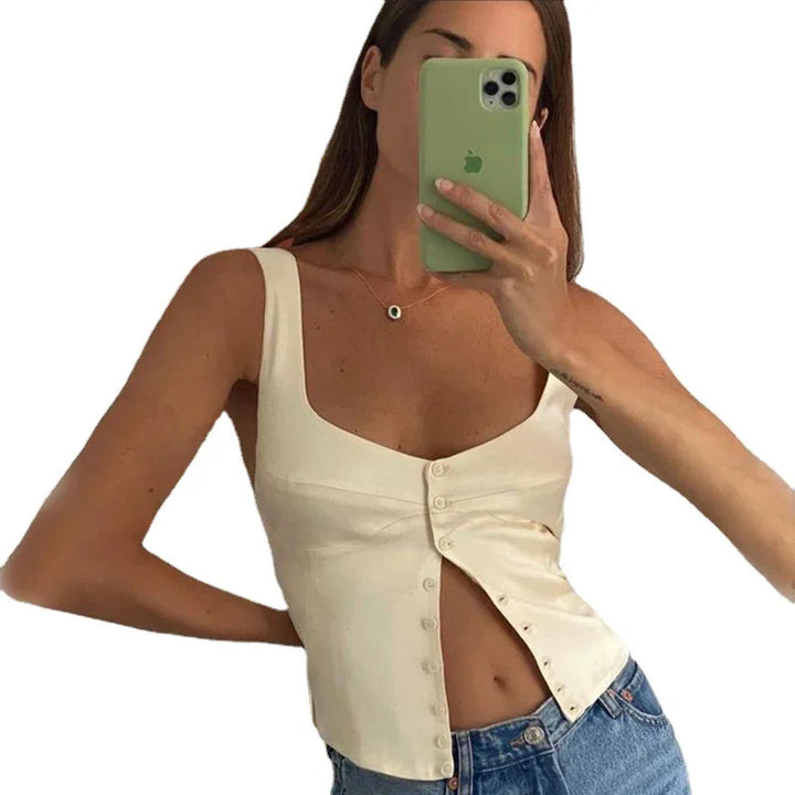 Woman wearing cream sleeveless buttoned top paired with blue denim jeans taking a mirror selfie