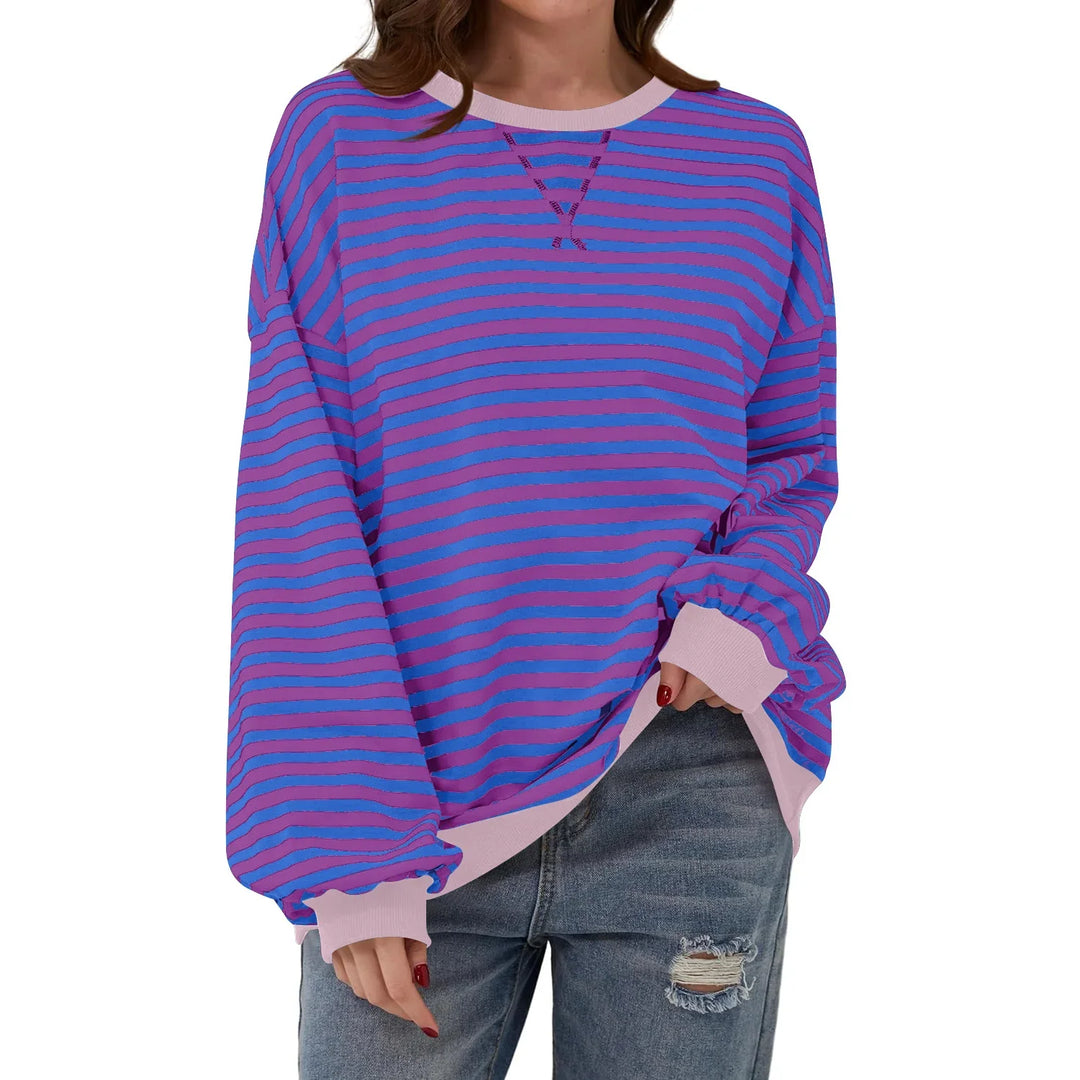 Woman wearing oversized long-sleeve purple and pink striped sweatshirt with ripped blue jeans