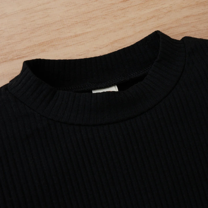 Close-up of black ribbed knit sweater neckline on wooden surface