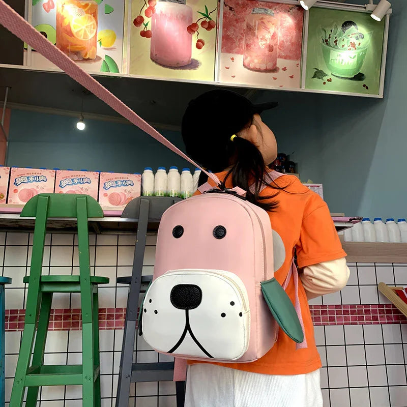 Child wearing pink dog face backpack and orange shirt in colorful cafe with fruit drink posters