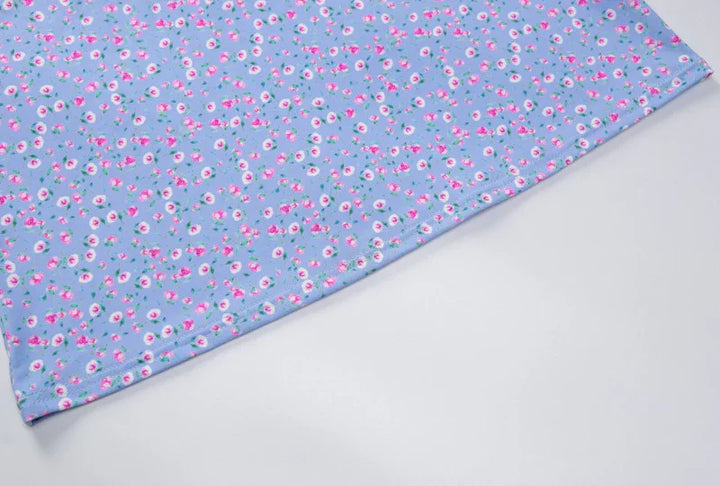 Blue fabric with small pink and white floral print pattern on light background