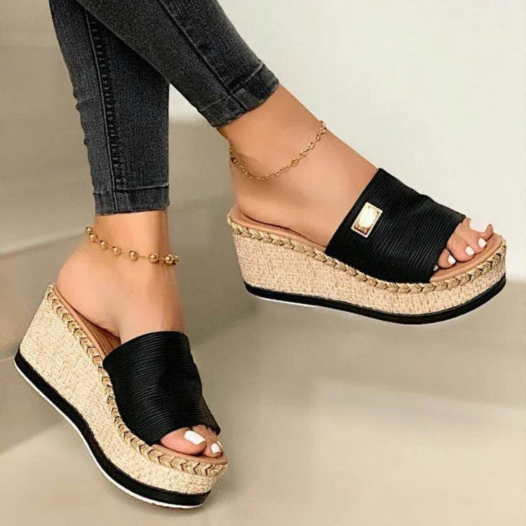 Wedge platform sandals with black straps and braided jute soles worn with anklets and dark jeans