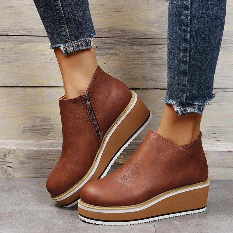 Brown leather platform wedge ankle boots with side zipper, worn with frayed hem blue jeans