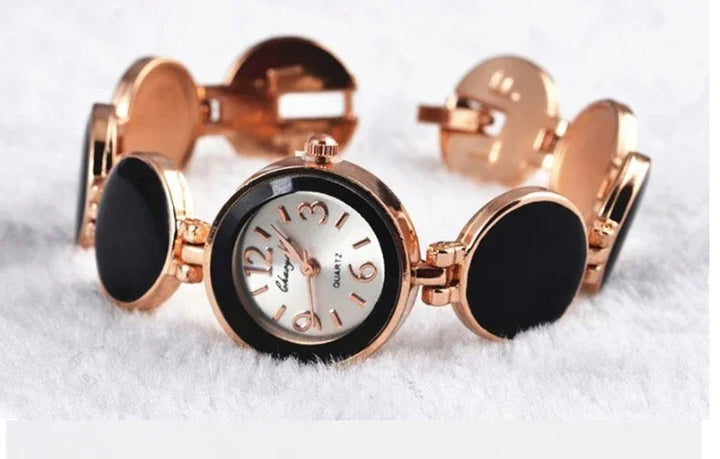 Elegant women's wristwatch with rose gold-tone case and black circular links on a white textured surface