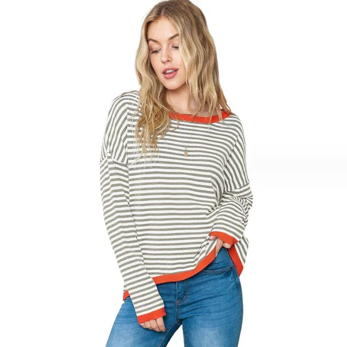 Woman wearing gray and white striped sweater with orange trim and blue jeans on white background