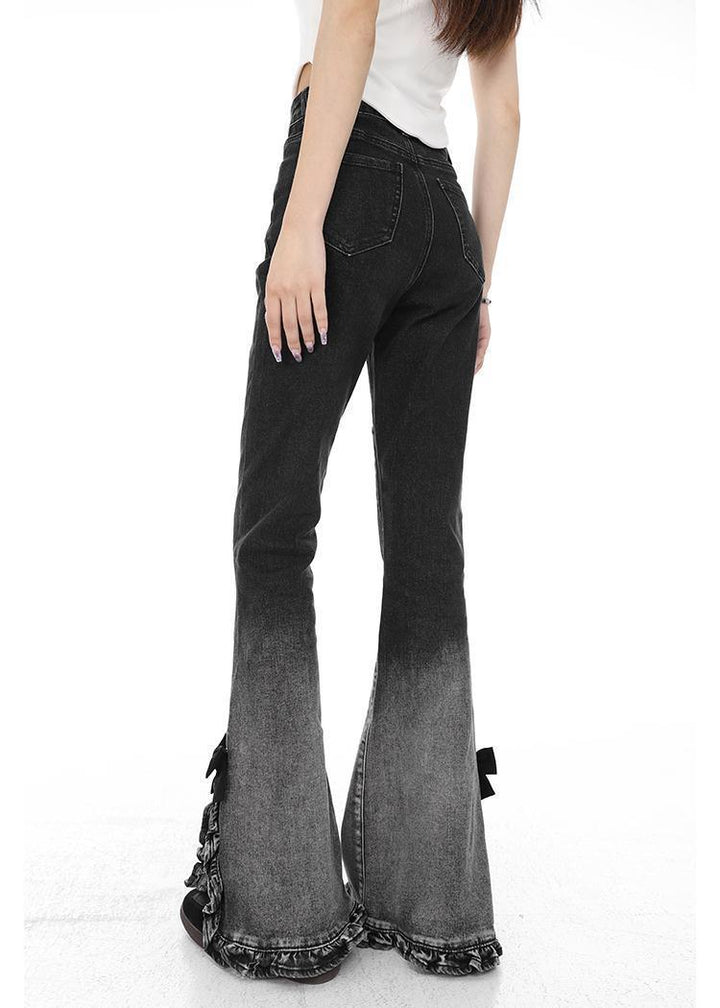 Woman wearing black to gray ombre flared jeans with ruffle detailing at the hem, shown from back
