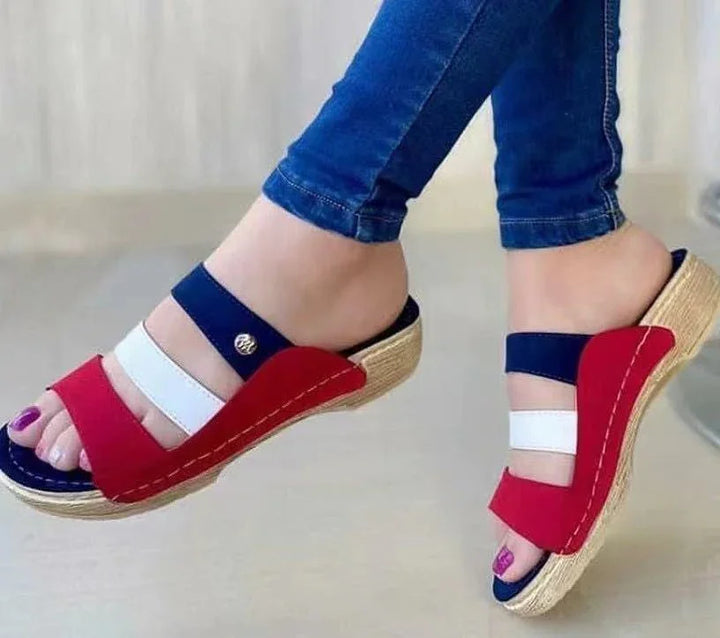 Close-up of feet wearing red, white, and blue wedge sandals with woven platform soles and purple nail polish