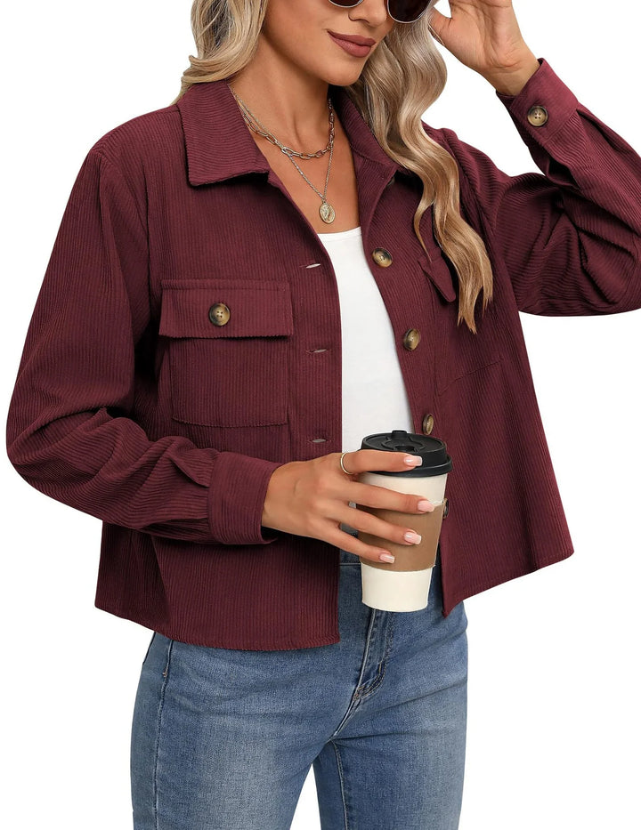 Woman wearing a maroon corduroy jacket with front pockets, holding a coffee cup, paired with blue jeans