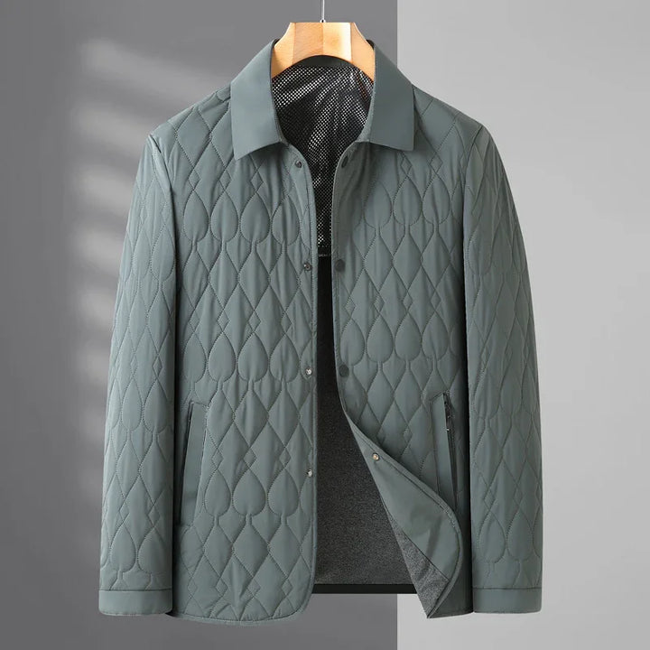 Gray quilted jacket with diamond and teardrop stitching, snap buttons, and collar on wooden hanger