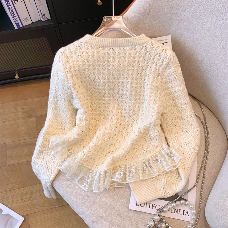 Cream knit sweater with delicate lace ruffle hem laid on beige chair and wooden floor