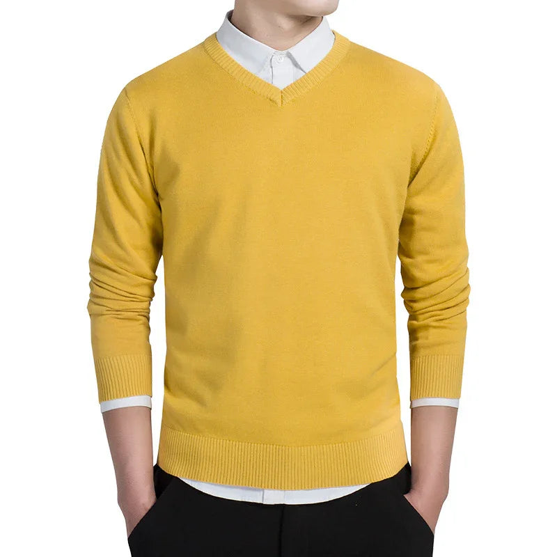 Man wearing mustard yellow V-neck sweater over white collared shirt with black pants